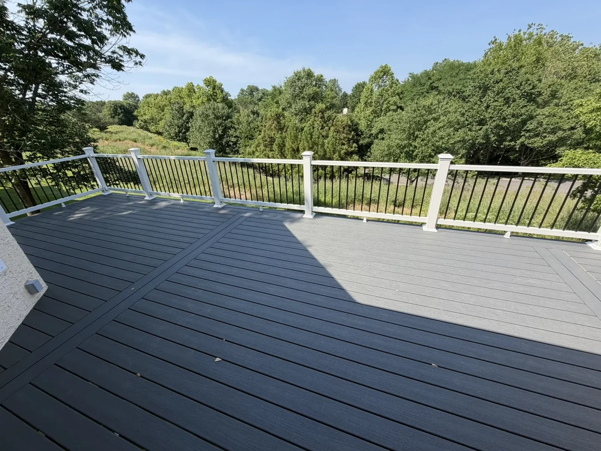 The deck looking outward over the railing to a mown field and mature tree line beyond.
