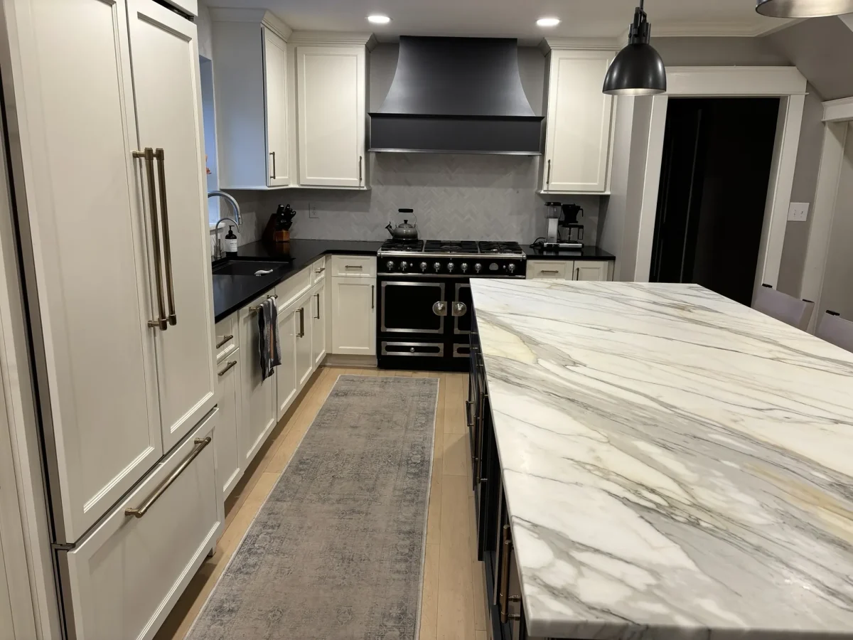 Full-height panelled refrigeration integrated into white cabinetry beside the marble island.