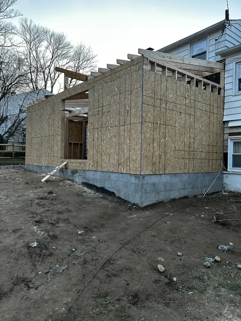 The addition framed and sheathed in plywood, roof structure complete and tied into the existing house.