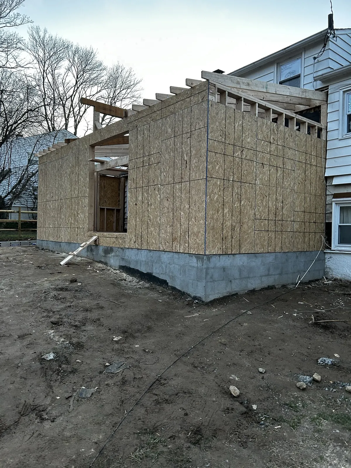 The addition framed and sheathed in plywood, roof structure complete and tied into the existing house.
