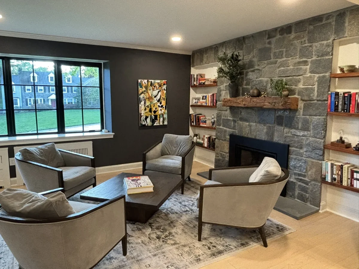 Seating arranged around the stone hearth, with a window seat built in beneath tall windows.
